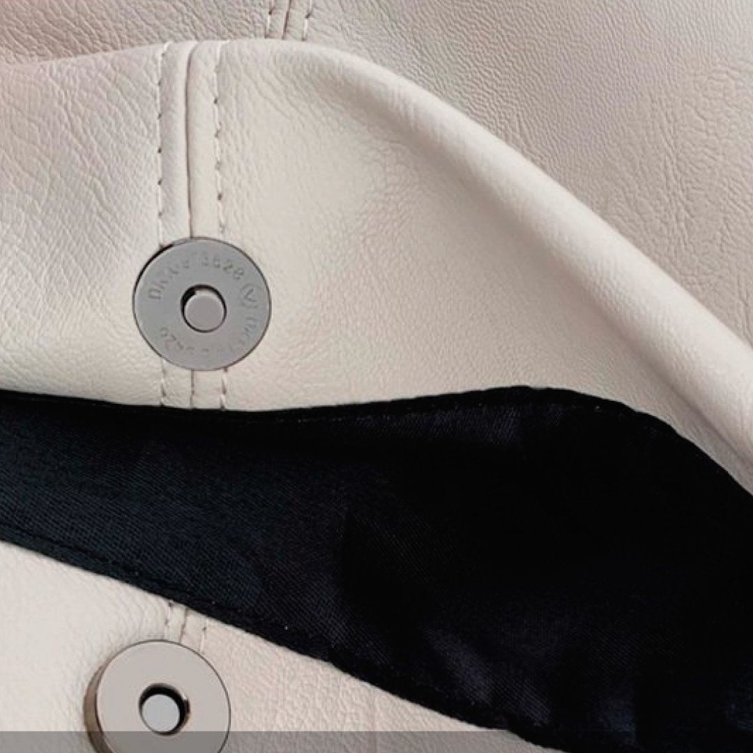 Ivory snap button panel with circular metal details on shoulder bag