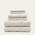 Ecru cotton towel stack with visible dobby medallion pattern across folded layers