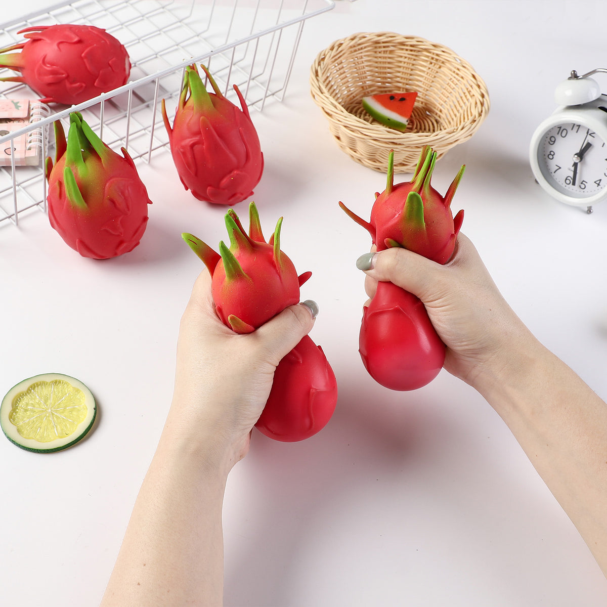 Red dragon fruit stress-relief gag toys with green leafy tops, two held in hands
