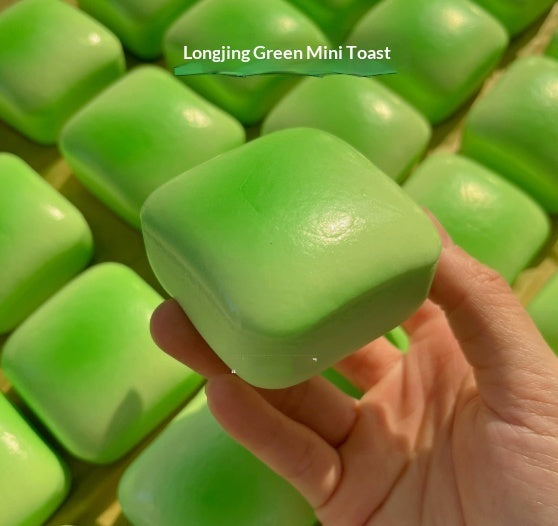 Bright green mini toast squishy squeeze toy with smooth surface, held in hand