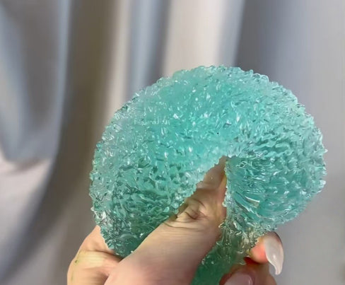 Light green textured bayberry squishy stress toy with stem, held up