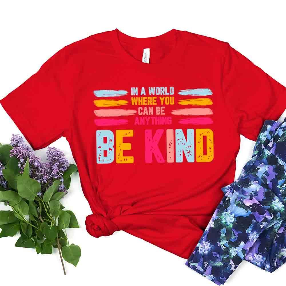 Red Be Kind slogan tee with colorful “BE KIND” print and layered brushstroke design