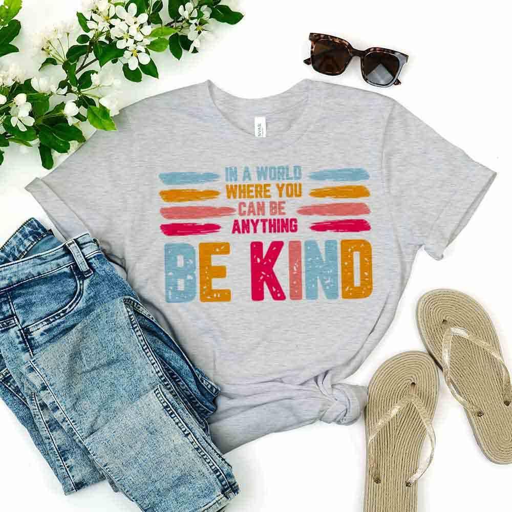 Heather gray Be Kind slogan tee with colorful “BE KIND” print and brushstroke stripes