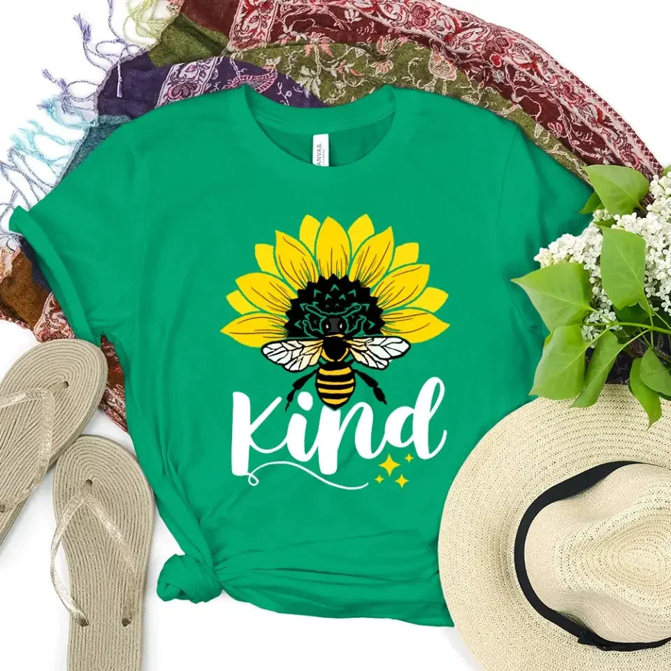 Green T-shirt with sunflower, bee, and “kind” graphic on the front.