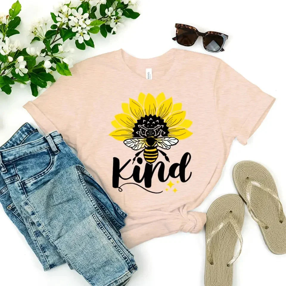 Peach T-shirt with sunflower, bee, and “kind” graphic on the front.