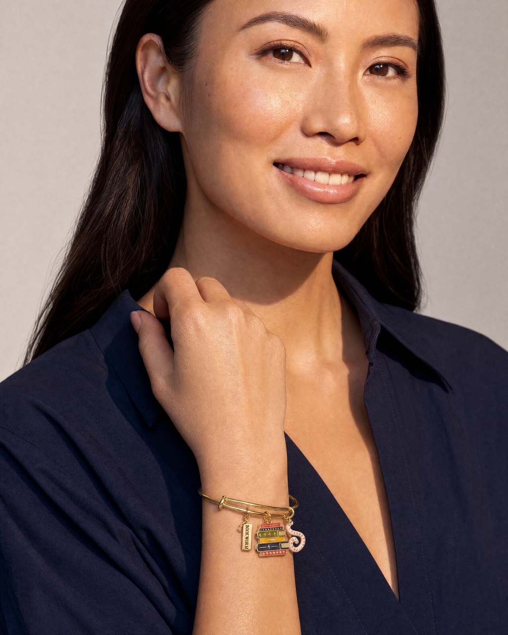 Gold charm bangle with book stack and pink octopus charms worn by model
