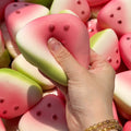 Watermelon slice squishy toy with dotted seed bumps, pressed by a hand