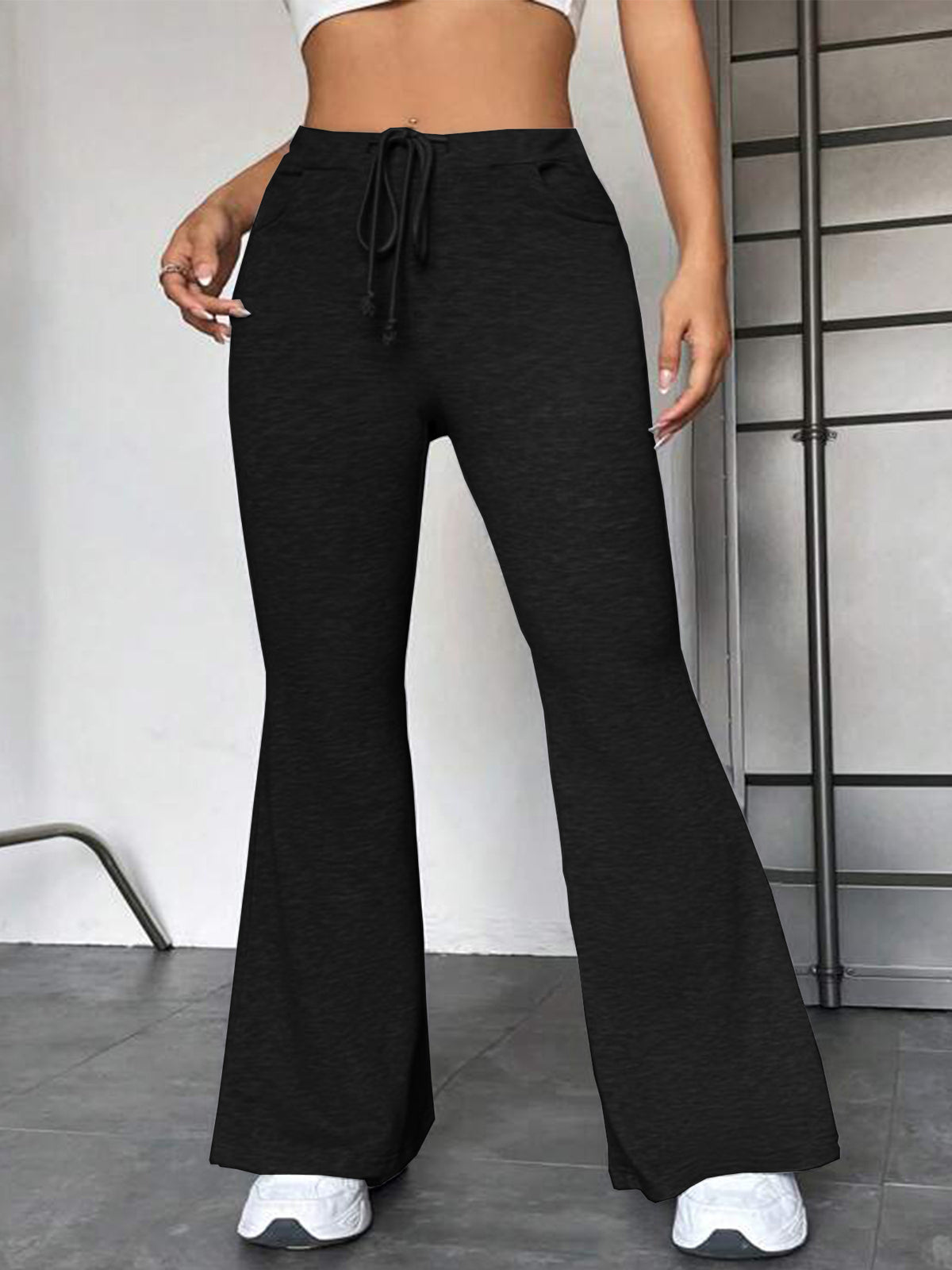 Black flared yoga pants with drawstring elastic waist and wide bell legs.
