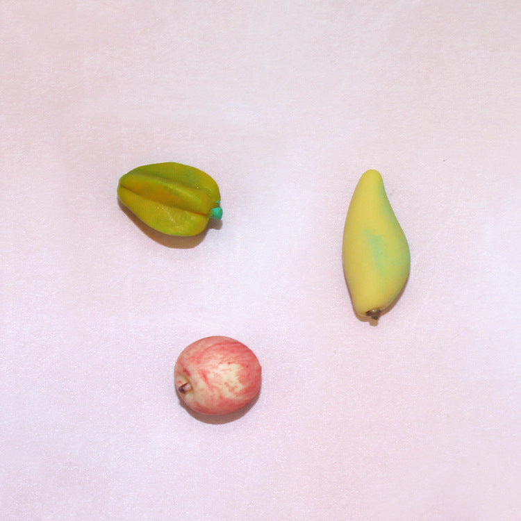 Assorted toy fruit pieces: green and yellow halves plus a red fruit