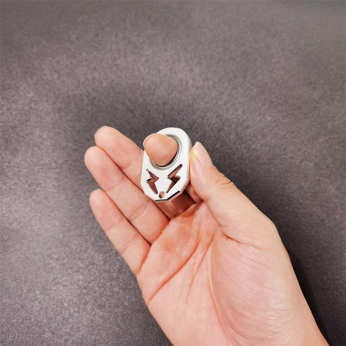 Silver rotating key chain held in a hand, with metal ring and arrow-style hook.