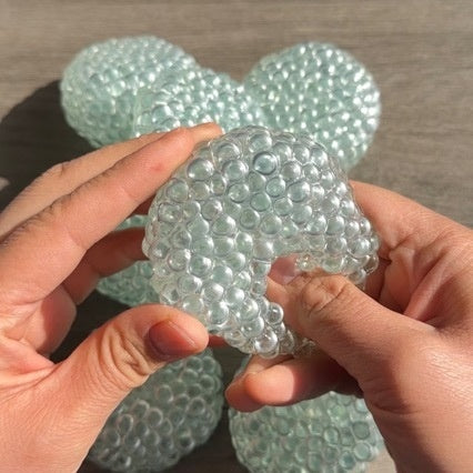 Clear textured stress-relief ball, bubble pattern, held between hands