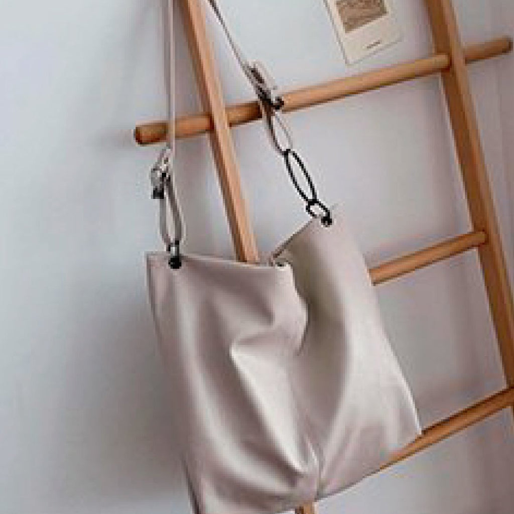 Ivory shoulder bag hanging with long strap and ring hardware, soft draped body