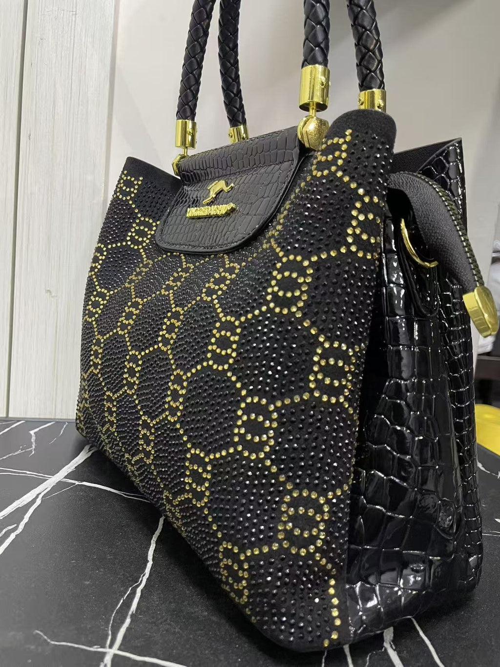 Black and gold studded crossbody bag with top handles, front flap, and side profile