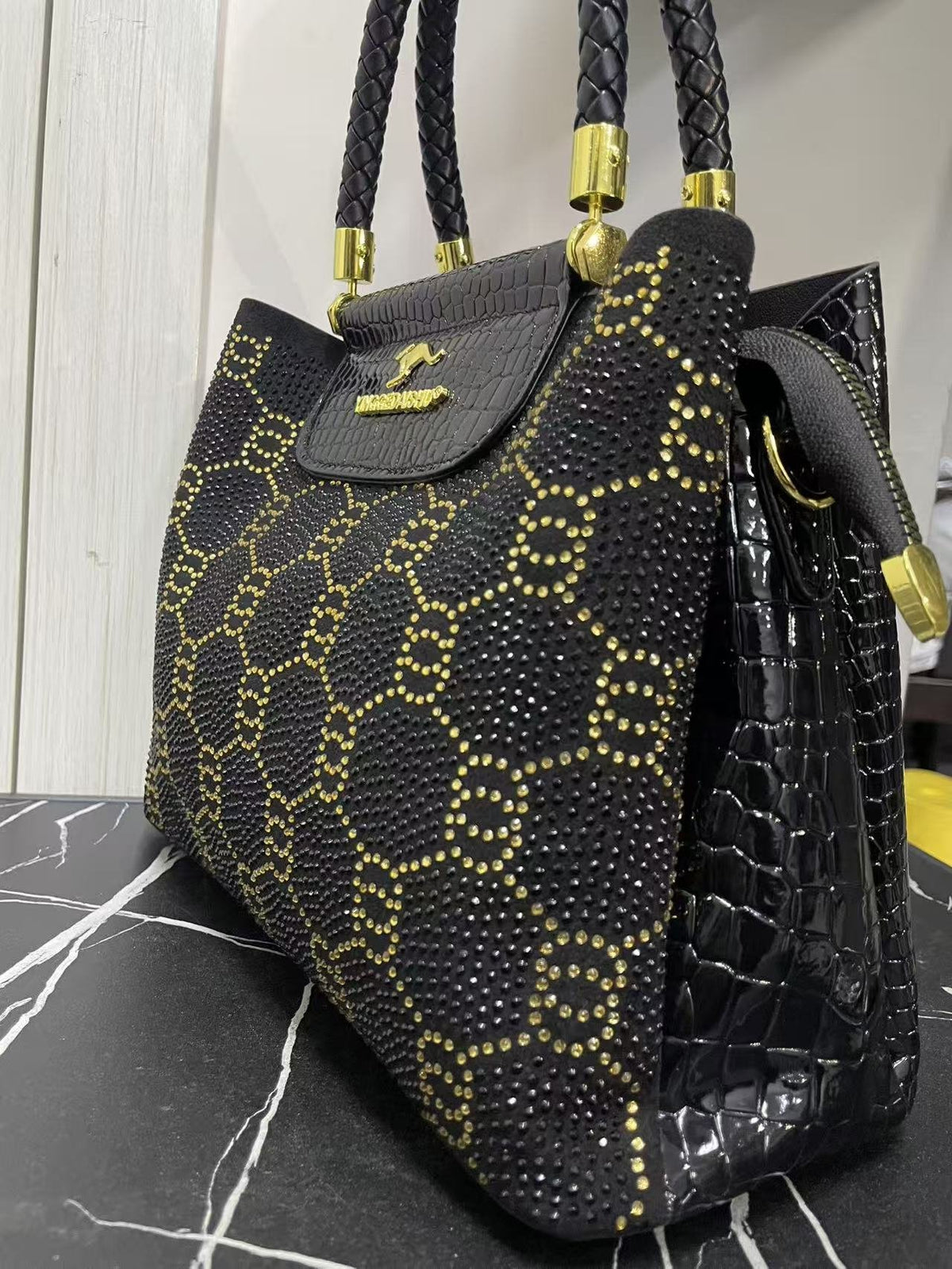 Black and gold studded crossbody bag with top handles, front flap, and side profile