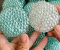 Two textured stress-relief balls: mint-green and clear, close-up bubbled texture