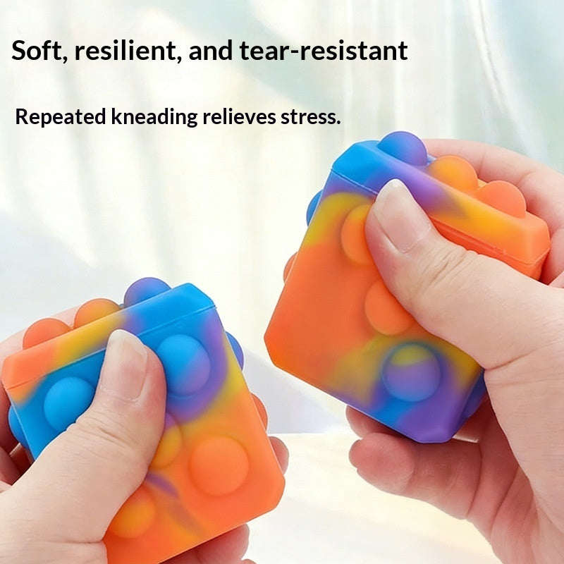 Square silicone bubble stress ball with rainbow bumps, held and squeezed by two hands