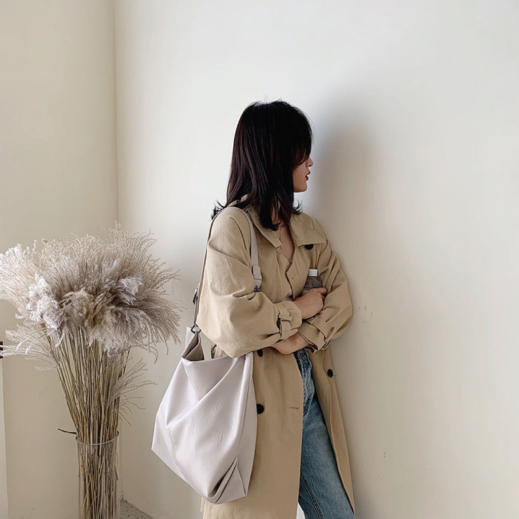 Ivory shoulder bag with ring strap hardware and slouchy tote shape