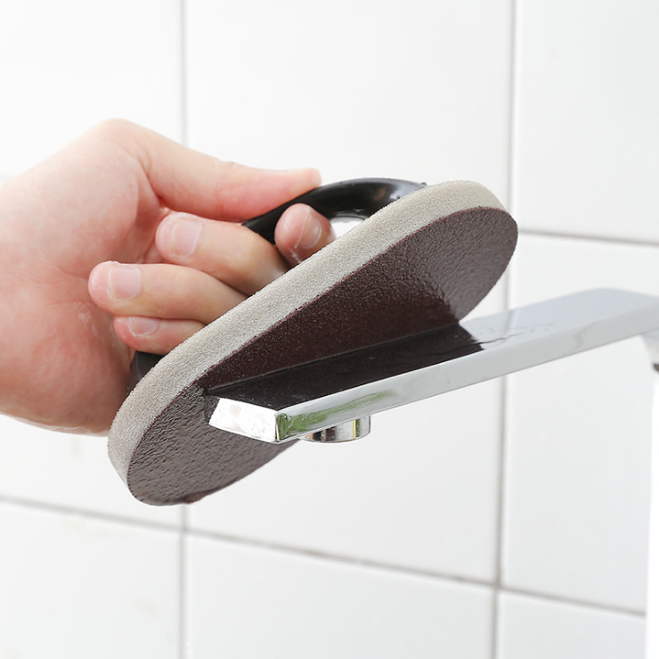 Emery cleaning tool with dark handle and gray pad used on a stovetop