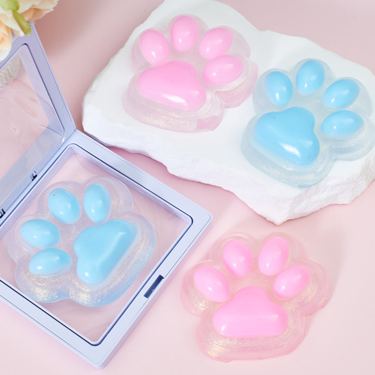 Translucent cat-paw squeeze toys in blue and pink, with matching boxed inserts