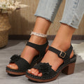 Black T-strap platform sandals with ankle buckle and flower embellishment