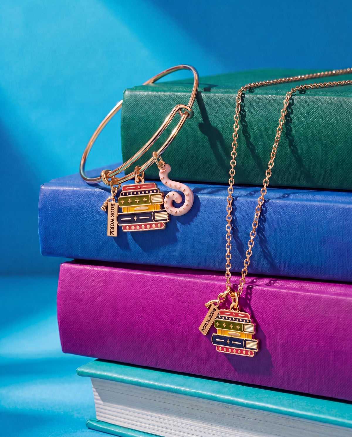 Gold charm bangle with stacked-book charms and pink octopus pendant charm