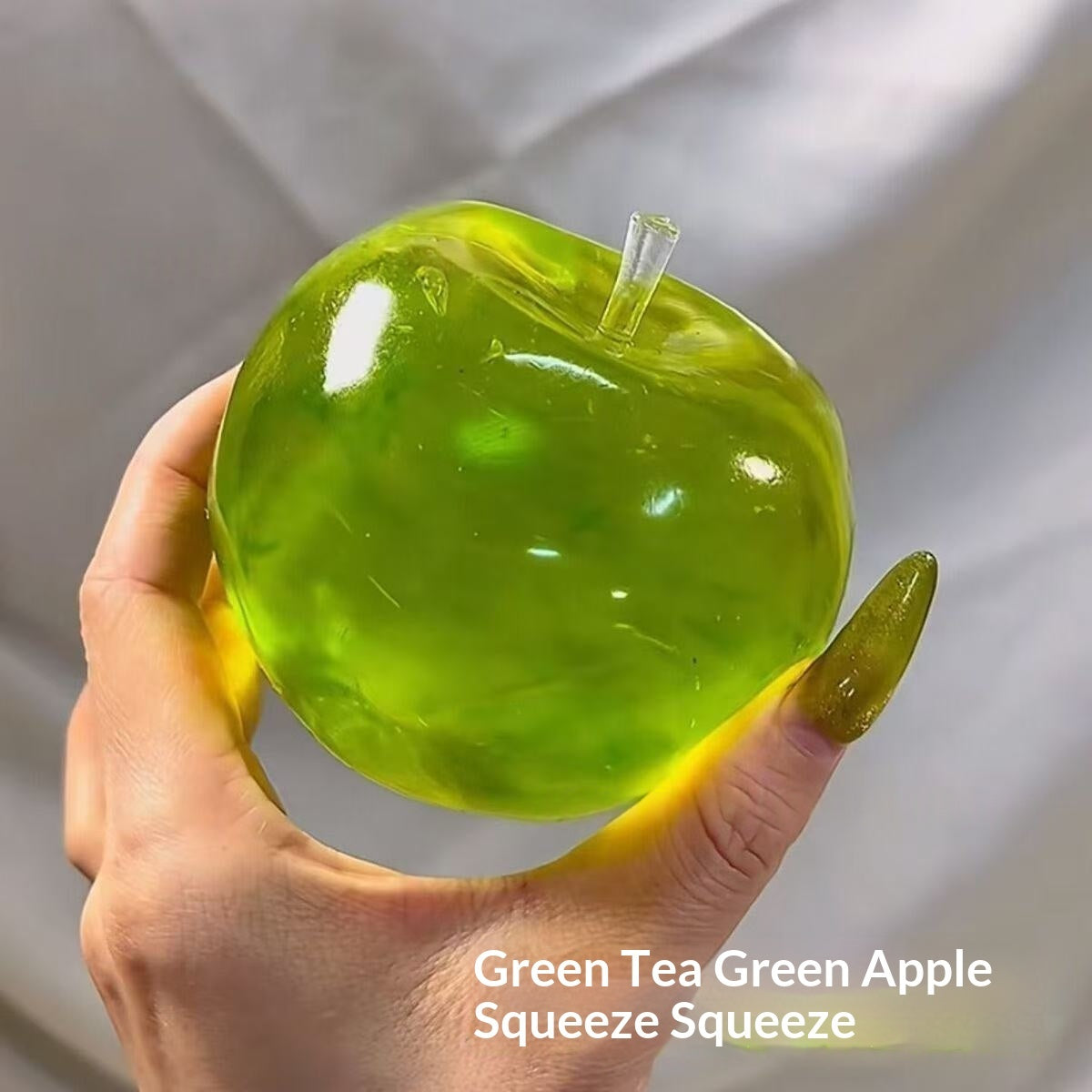 Green translucent apple-shaped stress squeeze toy with stem, held in hand