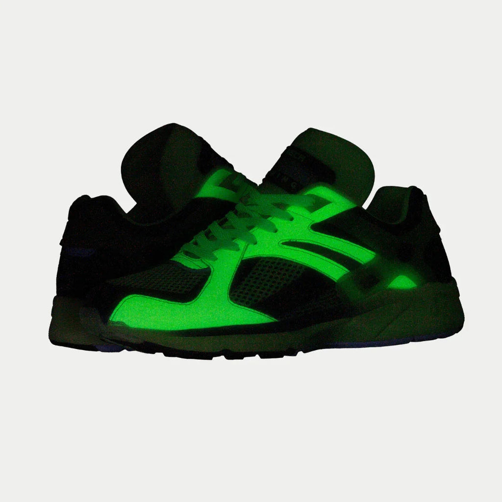 Men's neon yellow and black light-up lowtop sneaker glowing in dark lighting.