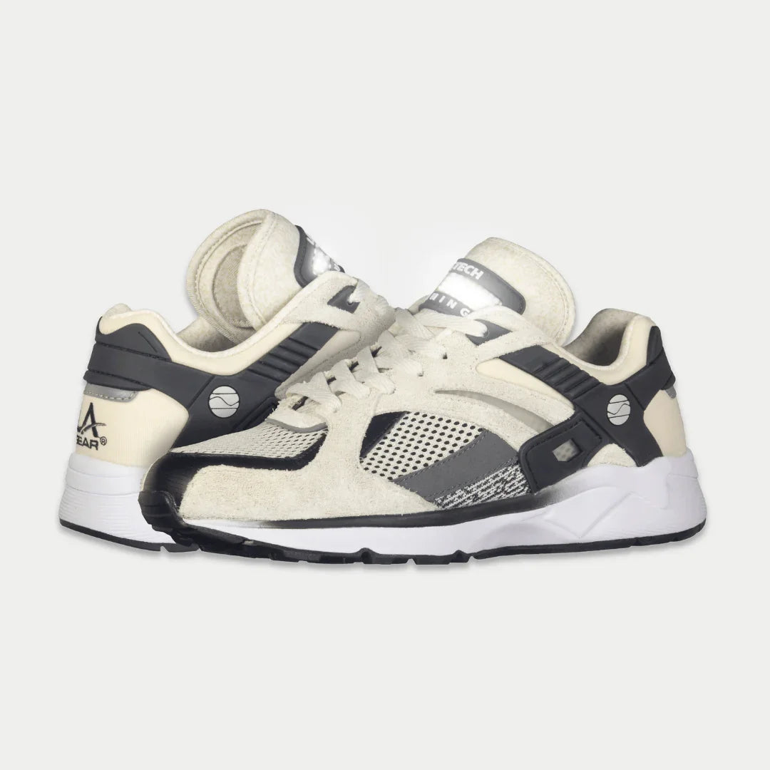 Women’s white and black lowtop sneakers, side view, lace-up with sporty mesh panels.