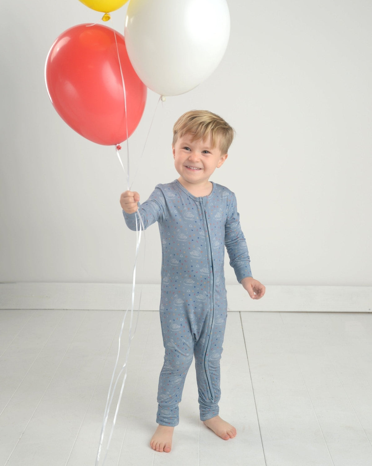 Blue long-sleeve toddler romper with zip fly and constellation print, standing view.
