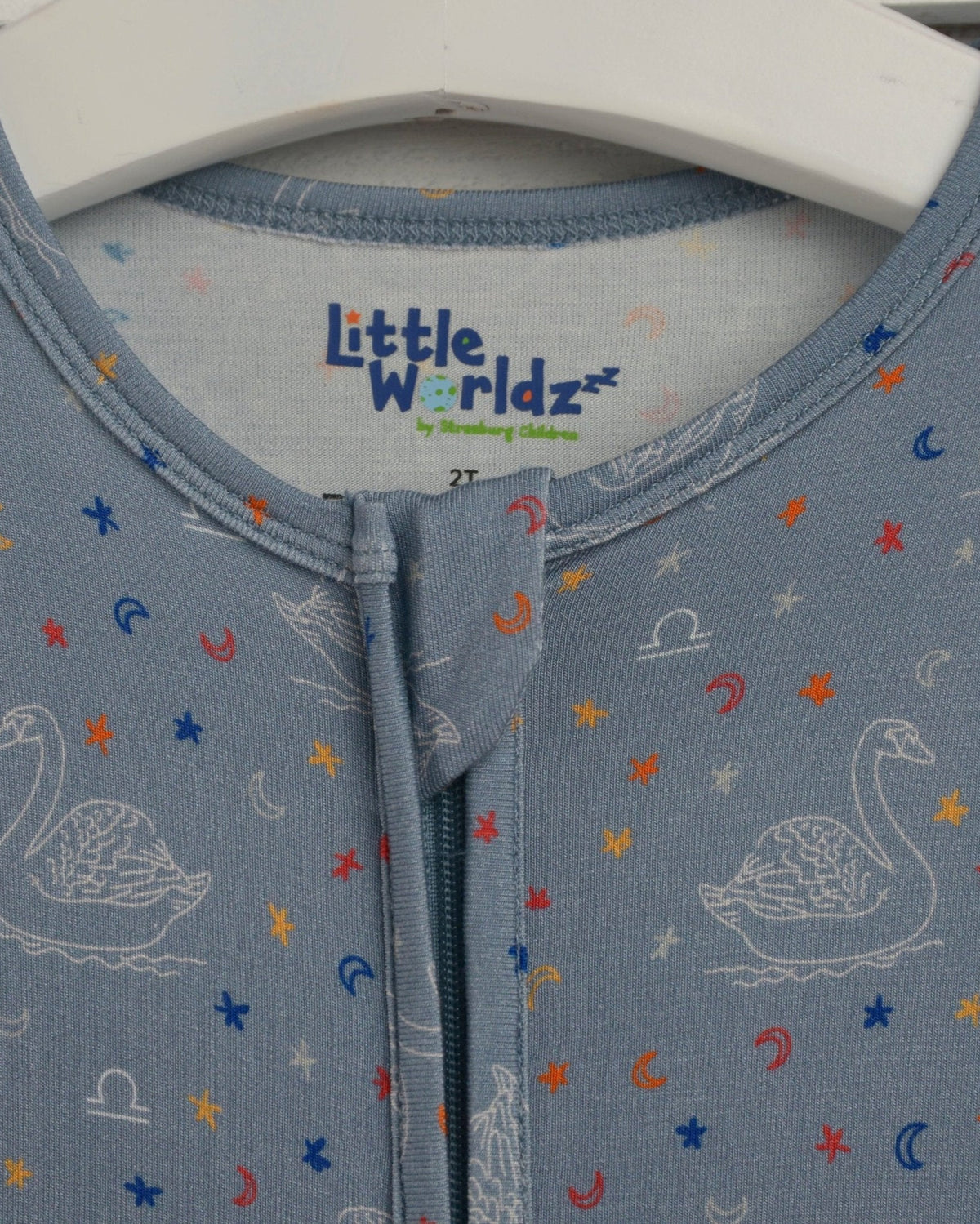Close-up of blue zip-front toddler romper with “Little Worldz” neck label.