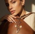 Golden flower bag charm with dangling heart, pearl, and floral square on leather strap