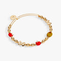 Gold-tone beaded bangle bracelet with red and yellow beads and decorative charm links