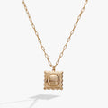 Gold locket pendant necklace with scalloped frame and reflective center on a chain