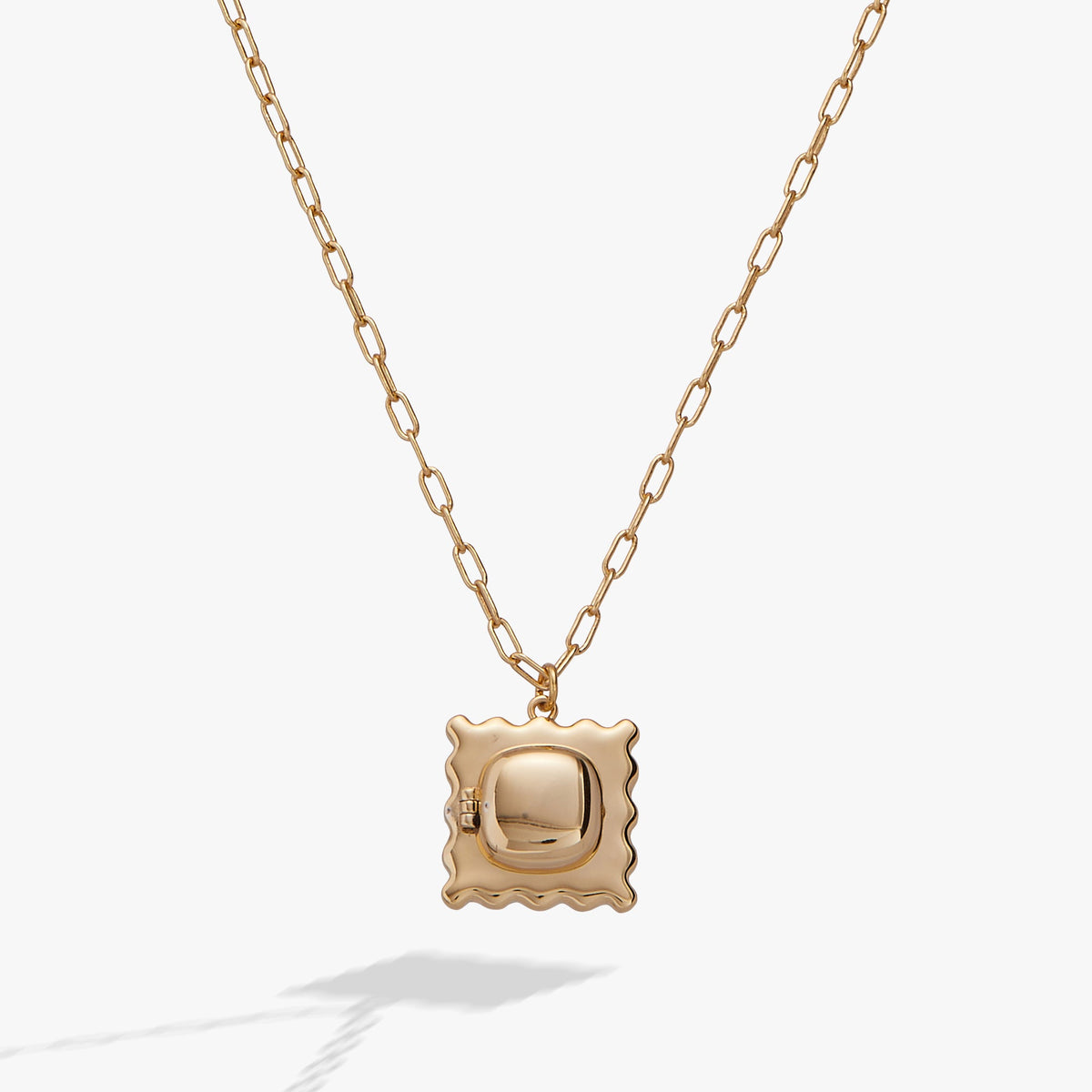 Gold locket pendant necklace with scalloped frame and reflective center on a chain