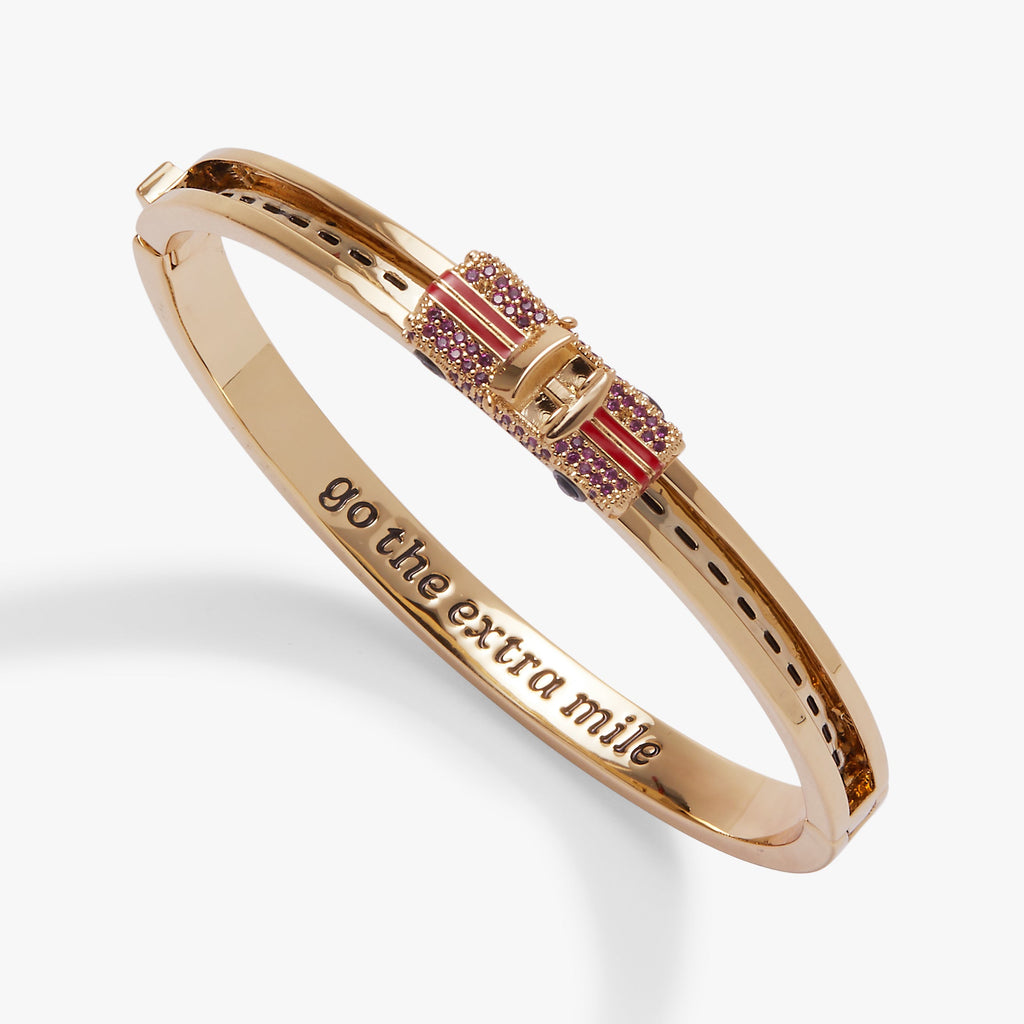 Gold-tone car fidget bangle with pink crystal strap and “go the extra mile” engraving