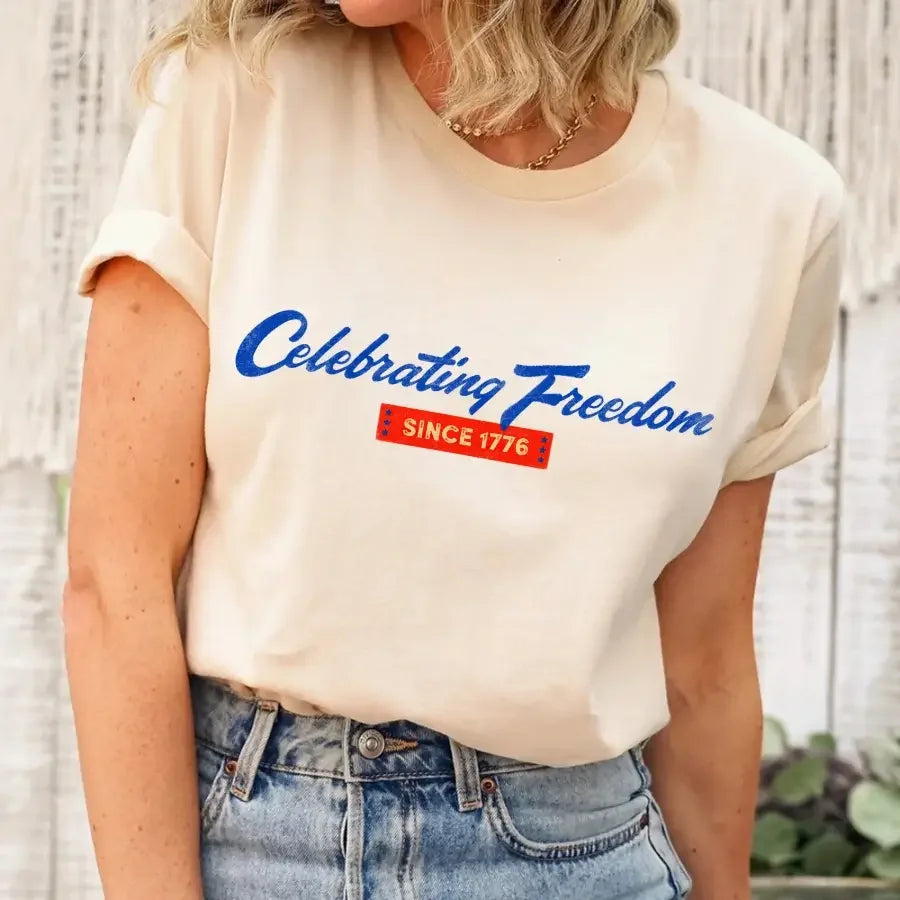 Cream women's graphic T-shirt with blue 'Celebrating Freedom' and 'Since 1776' print