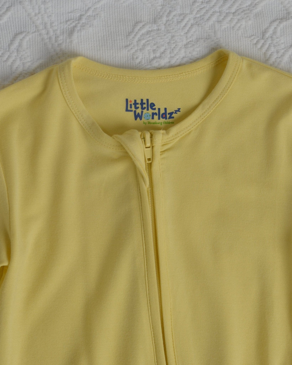 Yellow toddler romper pajamas with front zipper and Little Worldz logo