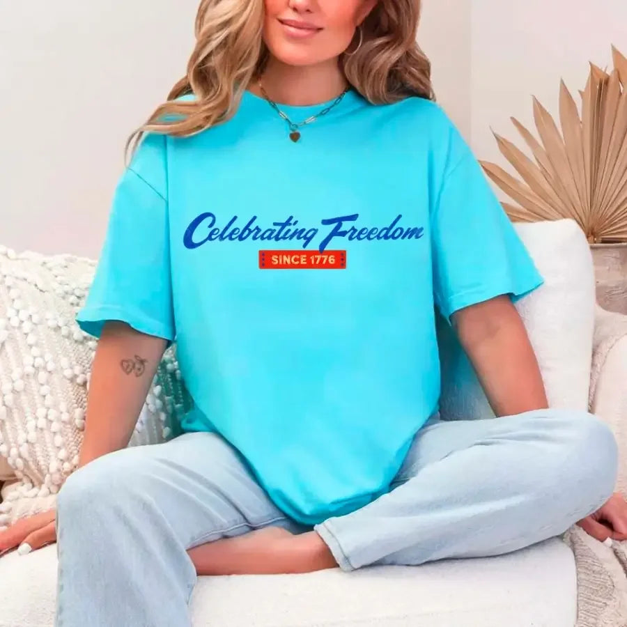 Turquoise women's graphic T-shirt with 'Celebrating Freedom' and 'Since 1776' print